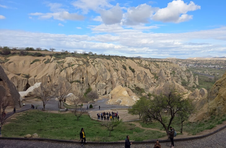 Göreme Açık Hava Müzesi giriş yolu ve çevresindeki doğal kaya oluşumları, ziyaretçiler yürüyüş yaparken görülüyor.